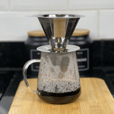 jarra de vidro transparente com filtro de aço inox preparando café em cima da bancada da cozinha